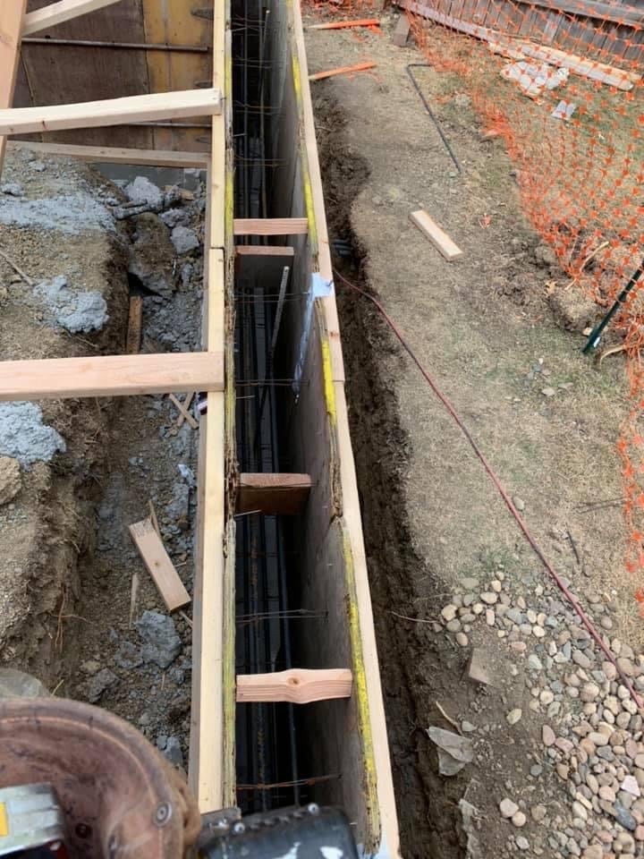 Foundation trench with reinforcement bars and concrete being laid during construction site work