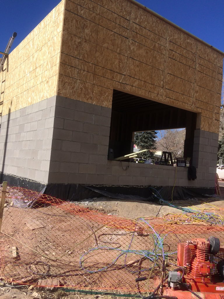Modern construction site with unfinished brick and concrete building structure featuring large window opening against blue sky