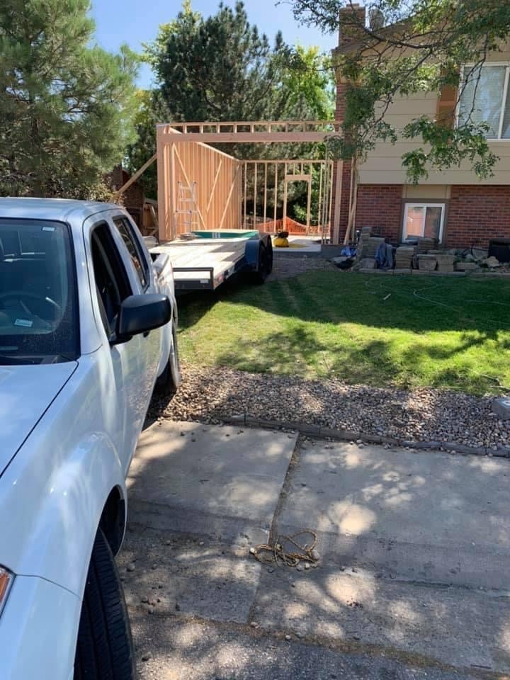 White pickup truck parked in driveway with wooden construction frame and brick house in background