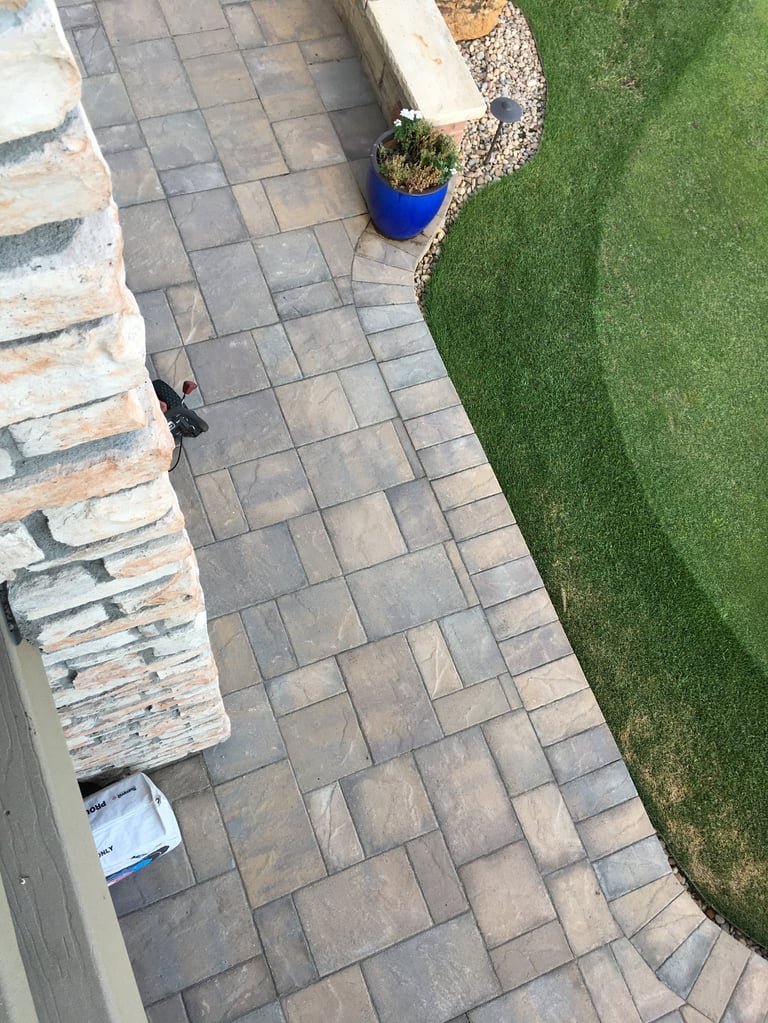Overhead view of a patio with stone pavers, blue planter pot, and adjacent green lawn