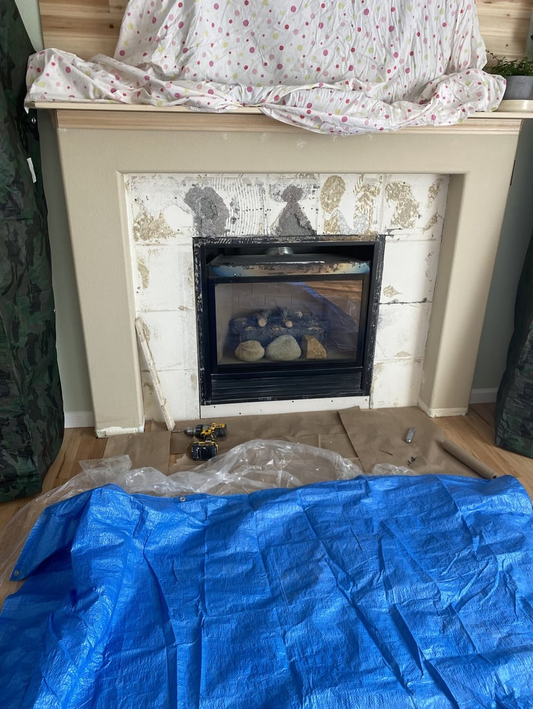 Fireplace under renovation with protective coverings and blue tarp on hardwood floor during home renovation