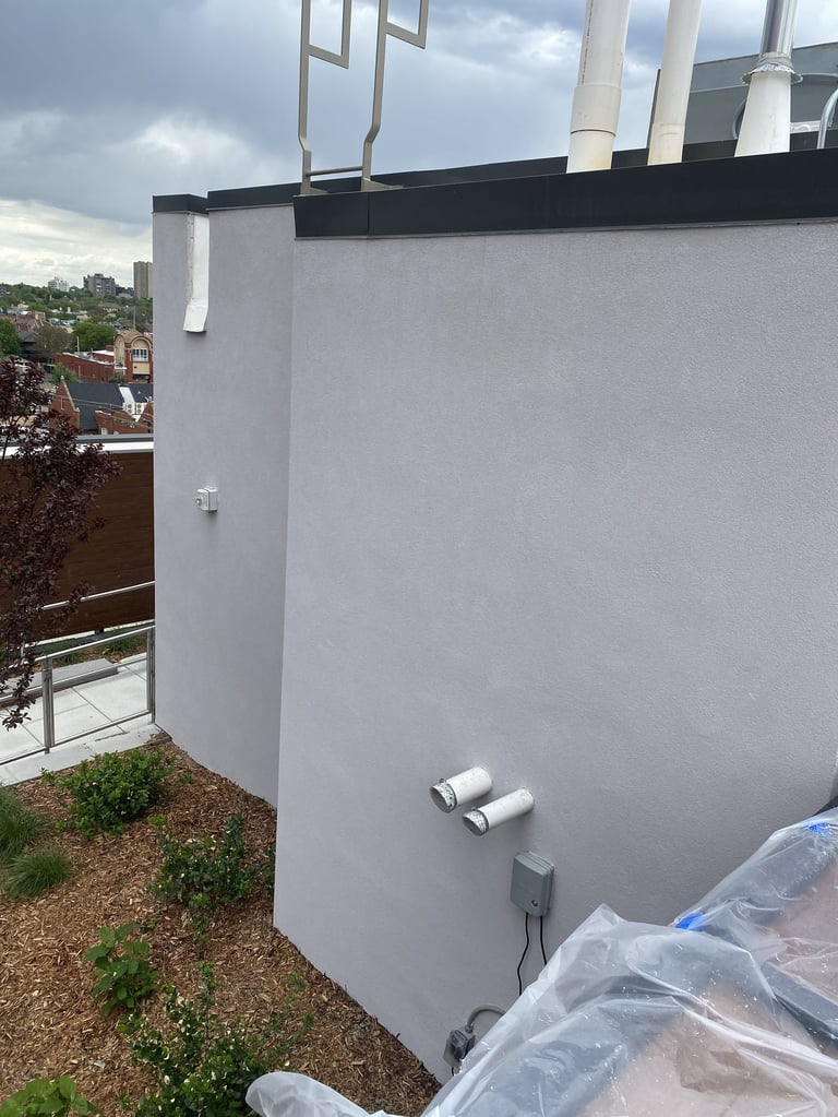 Modern gray cylindrical water tank on rooftop with ventilation pipes and city skyline in background