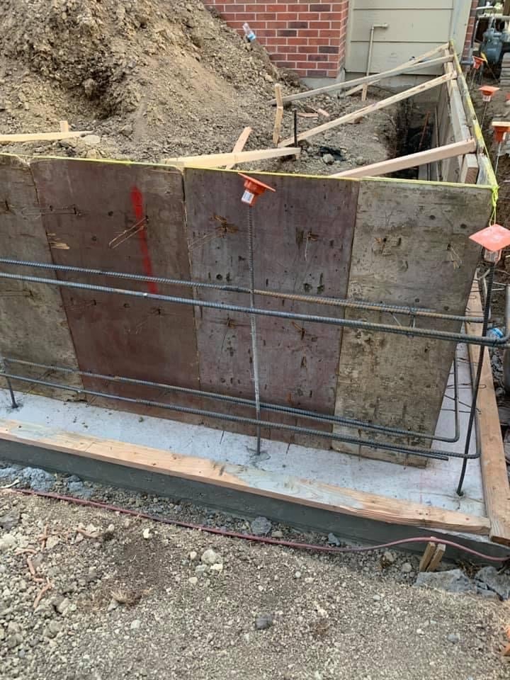 Metal dumpster bin filled with gravel and sand at construction site next to red brick building